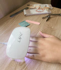 Pop-Up Mākeke - Iwi Nails - Gel Nail Strips - Pūpū Pōniuniu 1 (Hebrew Cone) - Gel Lamp in Use